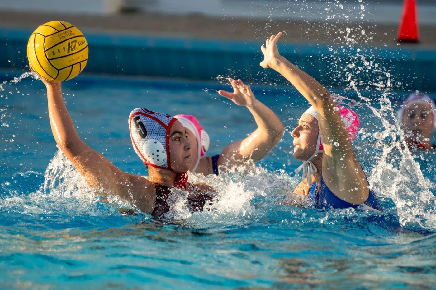 Une joueuse de water-polo protège le ballon face à une adversaire.