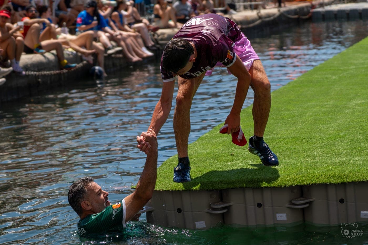 Un joueur tend la main à son coéquipier tombé à l'eau.