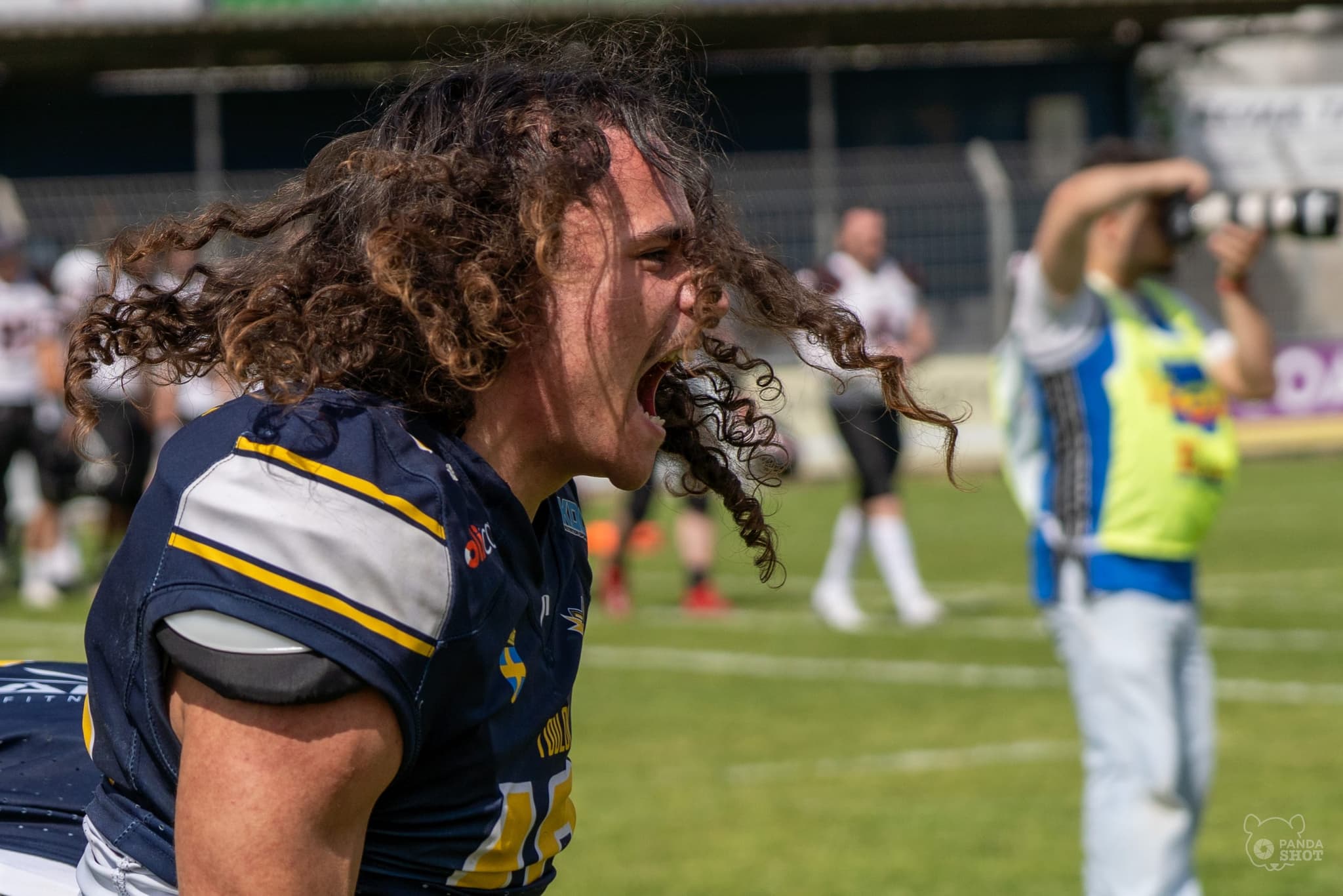 Un joueur de football américain hurle sa joie sur le terrain, casque retiré.